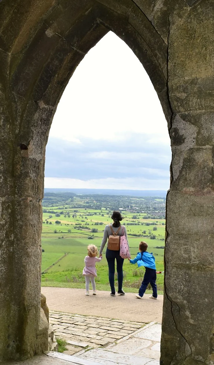 Elisabet con sus hijos, de espaldas, mirando el paisaje desde un arco de piedra